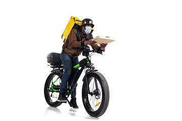 Image showing Too much orders. Contacless delivery service during quarantine. Man delivers food and shopping bags during isolation, wearing helmet and face mask.