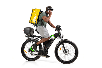 Image showing Too much orders. Contacless delivery service during quarantine. Man delivers food and shopping bags during isolation, wearing helmet and face mask.