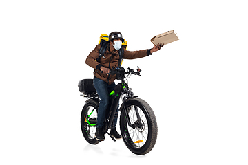 Image showing Too much orders. Contacless delivery service during quarantine. Man delivers food and shopping bags during isolation, wearing helmet and face mask.