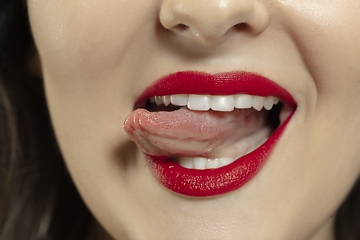 Image showing Smiling girl opening her mouth with red lips and showing the long big giant tongue isolated on white background, crazy and attracted, close up