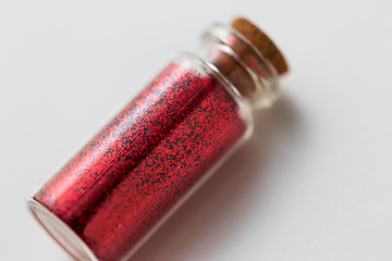 Image showing red glitters in bottle over white background