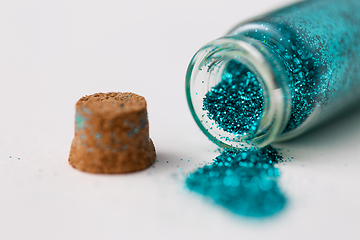 Image showing blue glitters poured from small glass bottle