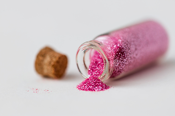 Image showing pink glitters poured from small glass bottle