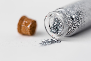 Image showing silver glitters poured from small glass bottle