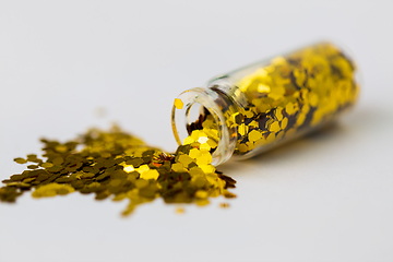 Image showing golden glitters poured from small glass bottle