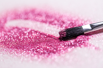 Image showing make up brush making stroke on pink glitters