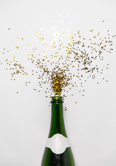 Image showing champagne bottle and golden glitters on white