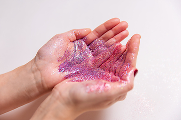 Image showing hands holding glitters on white background