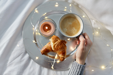 Image showing hand of woman drinking coffee with croissant