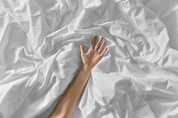 Image showing hand of woman lying on rumpled bed sheet