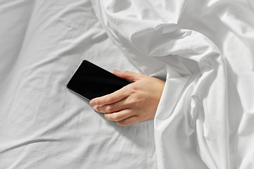 Image showing hand of woman lying in bed with smartphone