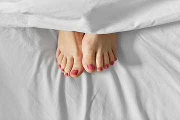 Image showing feet of woman lying in bed under white blanket