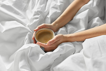 Image showing hands of woman with cup of coffee in bed