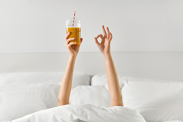 Image showing hands of woman lying in bed with cup of juice