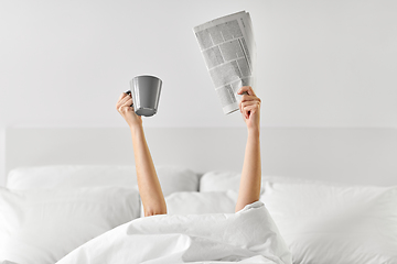 Image showing woman with coffee and newspaper lying in bed