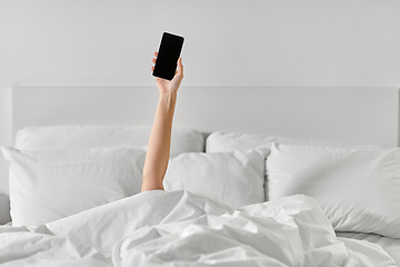 Image showing hand of woman lying in bed with smartphone