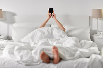 Image showing hands of woman lying in bed with smartphone