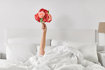 Image showing hand of woman lying in bed with bunch of flowers