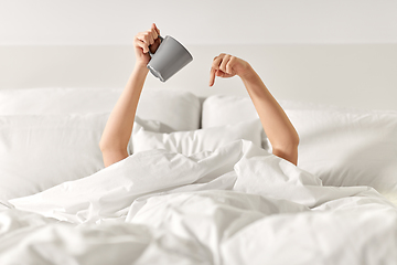 Image showing woman with cup of coffee lying in bed