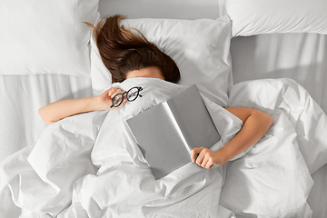 Image showing woman lying in bed with book and glasses