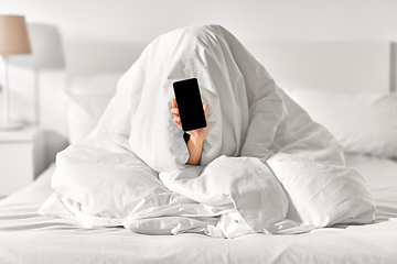 Image showing woman with phone sitting under blanket in bed