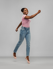 Image showing happy african american woman jumping over grey