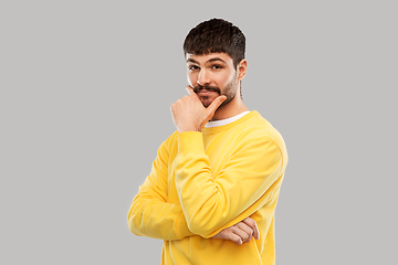 Image showing thinking young man in yellow sweatshirt