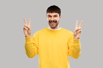 Image showing young man showing peace over grey background