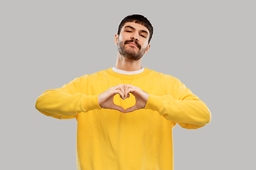 Image showing young man in yellow sweatshirt l making hand heart