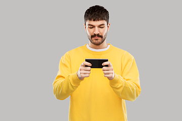 Image showing young man playing game on smartphone