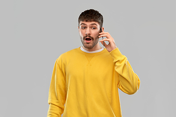 Image showing shocked young man calling on smartphone