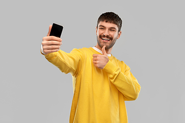 Image showing man takes selfie with phone and shows thumbs up