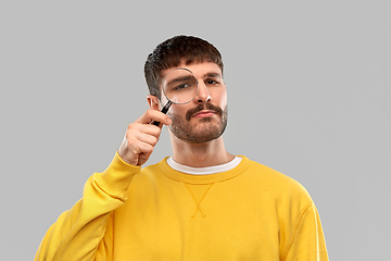 Image showing man in yellow sweatshirt with magnifier