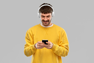 Image showing smiling young man with headphones and smartphone