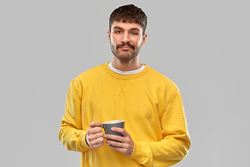 Image showing displeased young man with coffee cup