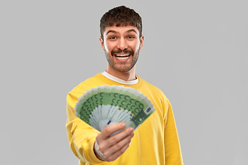 Image showing smiling young man in yellow sweatshirt with money