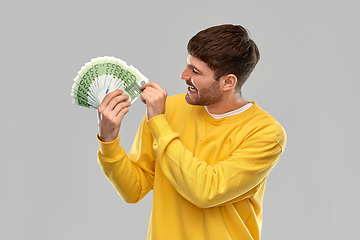 Image showing smiling young man in yellow sweatshirt with money