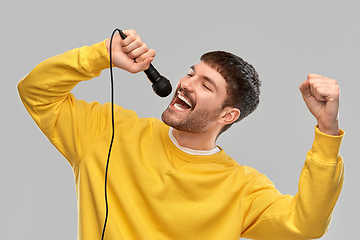 Image showing man in yellow sweatshirt with microphone singing