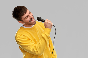 Image showing man in yellow sweatshirt with microphone singing