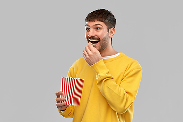 Image showing smiling man in yellow sweatshirt eating popcorn