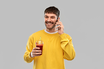 Image showing happy man with tomato juice calling on smartphone