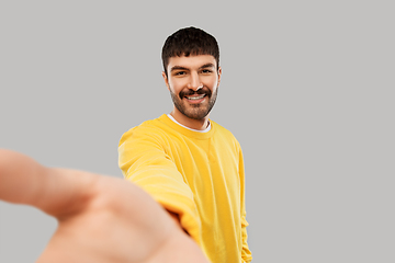 Image showing happy young man in yellow sweatshirt making selfie