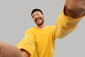 Image showing happy young man in yellow sweatshirt making selfie