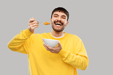 Image showing happy smiling young man eating cereals