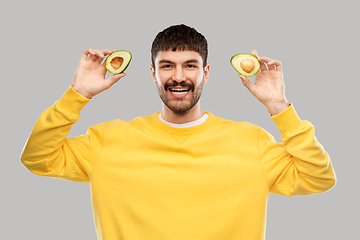 Image showing happy young man in yellow sweatshirt with avocado