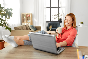 Image showing woman with laptop drinking coffee at home office