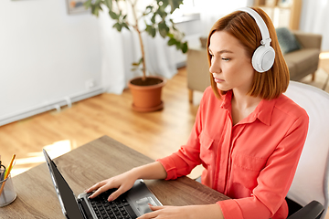 Image showing woman in headphones with laptop working at home