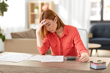 Image showing woman with calculator and papers working at home