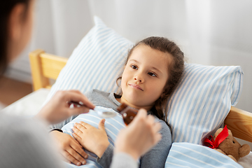 Image showing mother pouring cough syrup for sick daughter