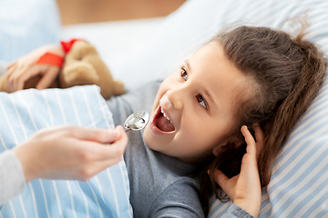 Image showing mother giving cough syrup to sick daughter